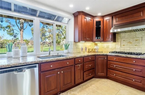 a kitchen with stainless steel appliances granite countertop wooden cabinets a sink and a large window