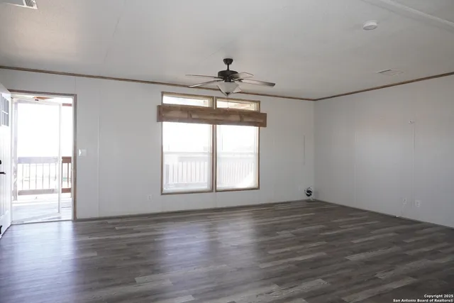 an empty room with wooden floor chandelier and windows