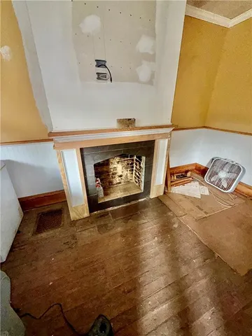 a view of an empty room with wooden floor and a fireplace