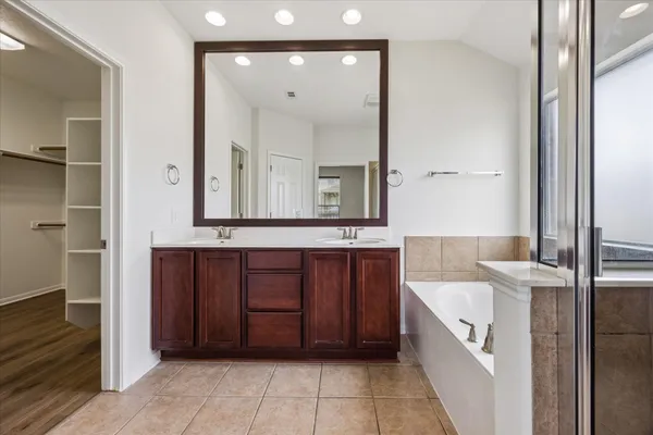 a bathroom with a tub a double vanity sink and mirror