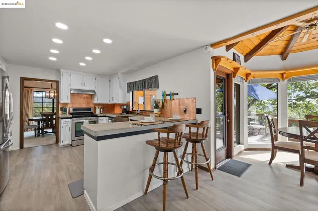 a kitchen with stainless steel appliances granite countertop dining table chairs and wooden floor