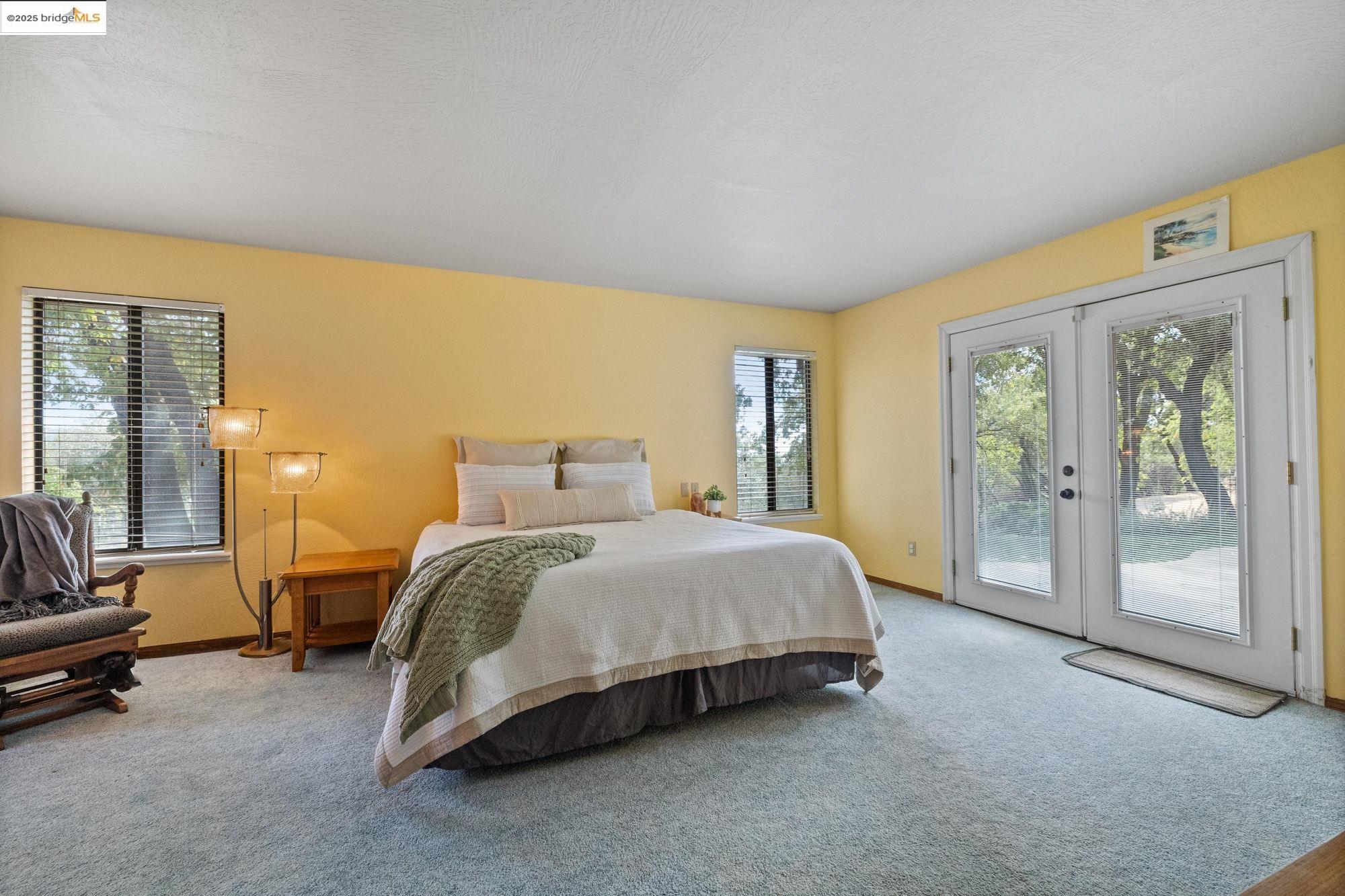 21950 Paseo De Los Portales Road Sonora, CA 95370 - Photo 26 of 47 a spacious bedroom with a bed and glass door