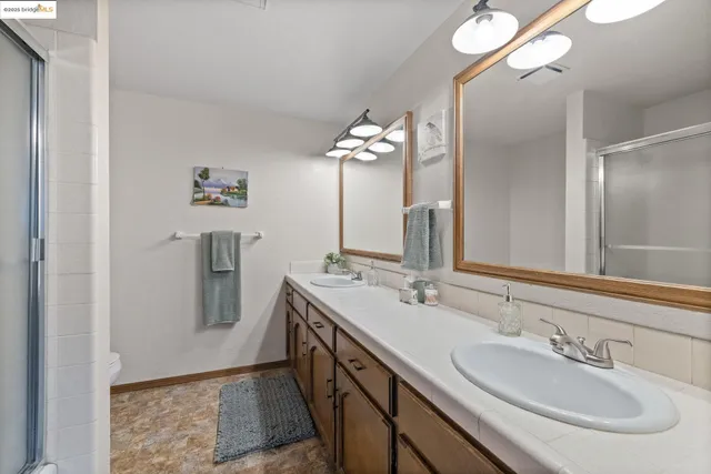 a spacious bathroom with a double vanity sink a mirror and a shower