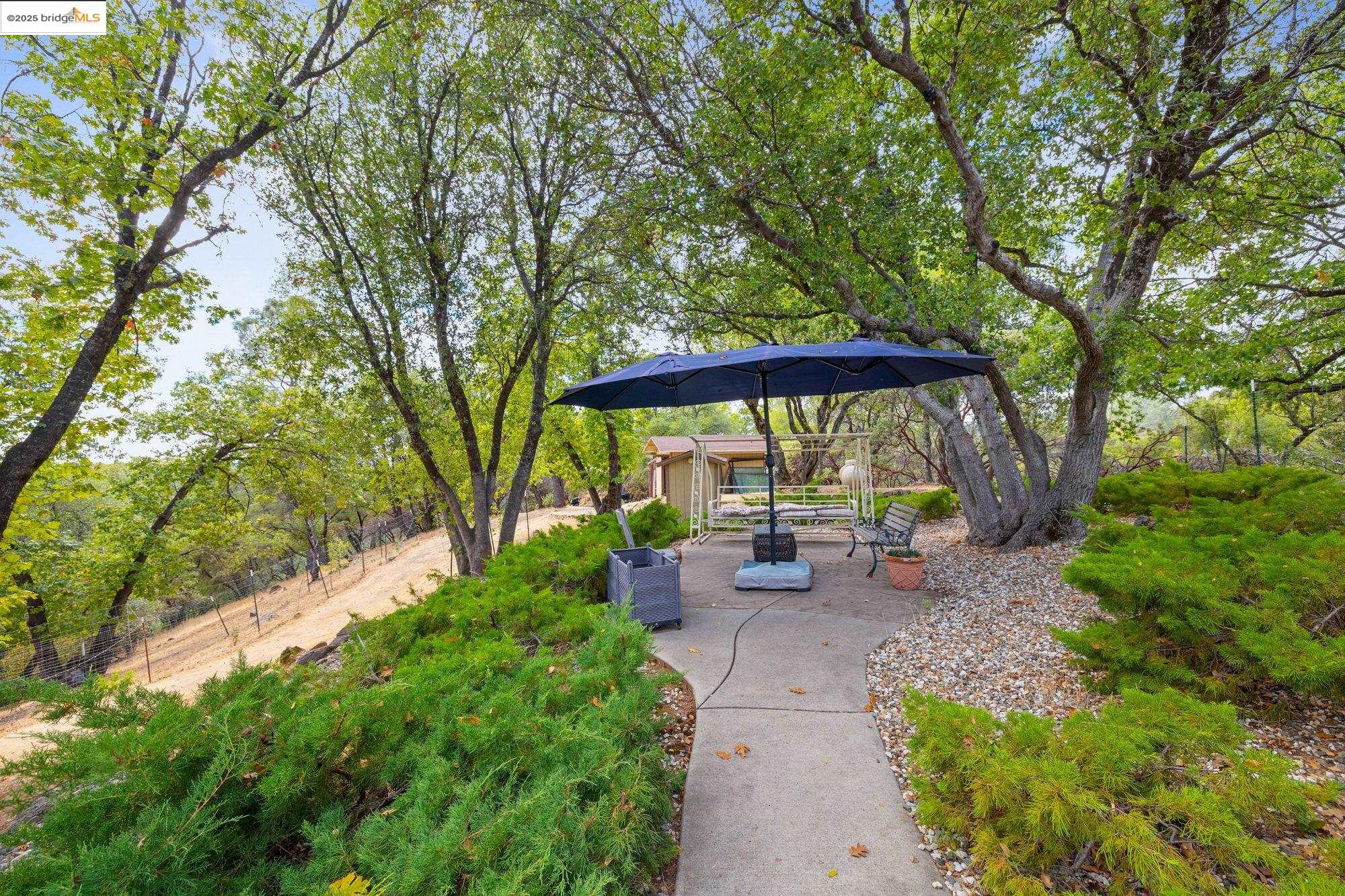 21950 Paseo De Los Portales Road Sonora, CA 95370 - Photo 41 of 47 a view of a patio with table and chairs under an umbrella