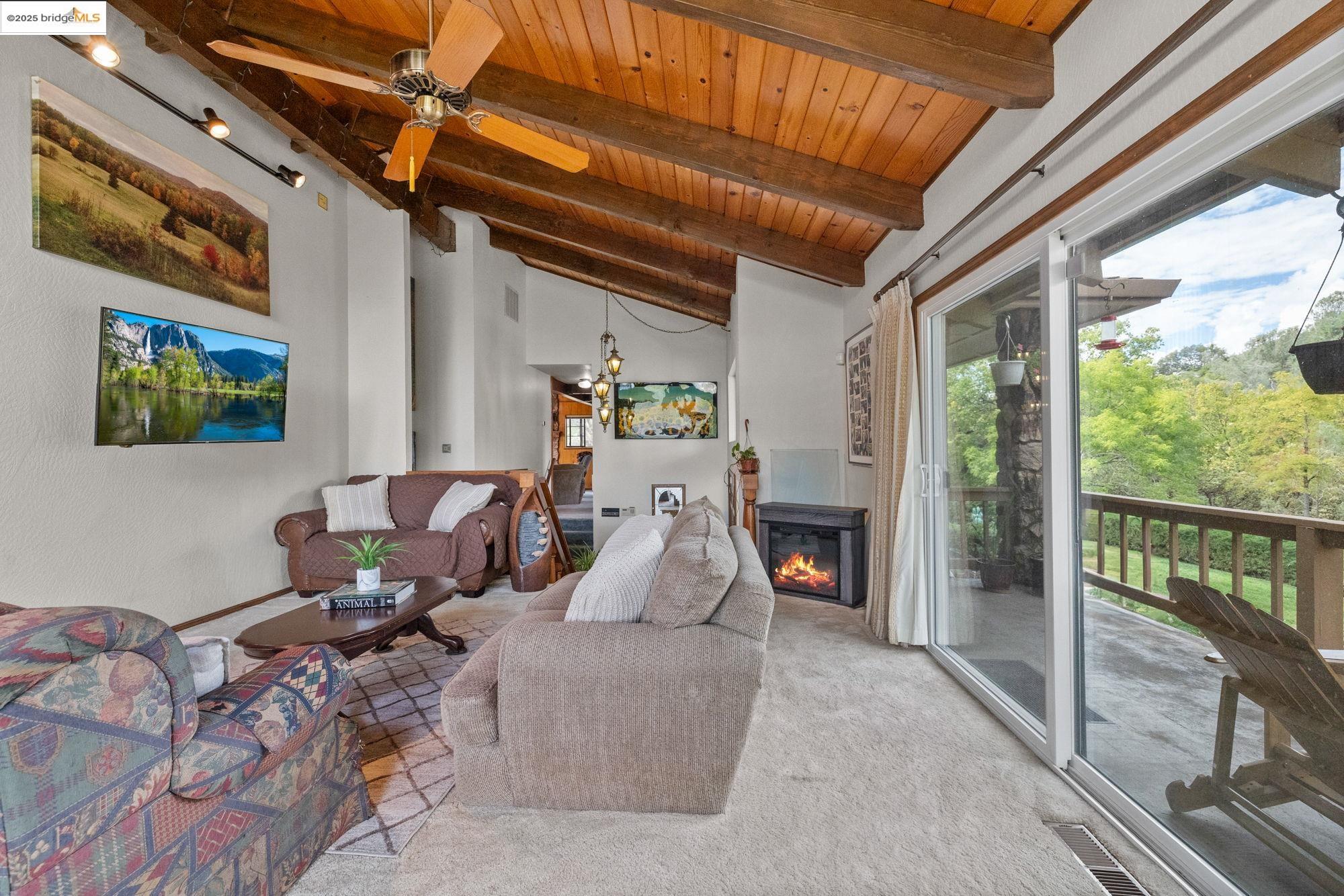 21950 Paseo De Los Portales Road Sonora, CA 95370 - Photo 5 of 47 a living room with furniture a fireplace and a floor to ceiling window