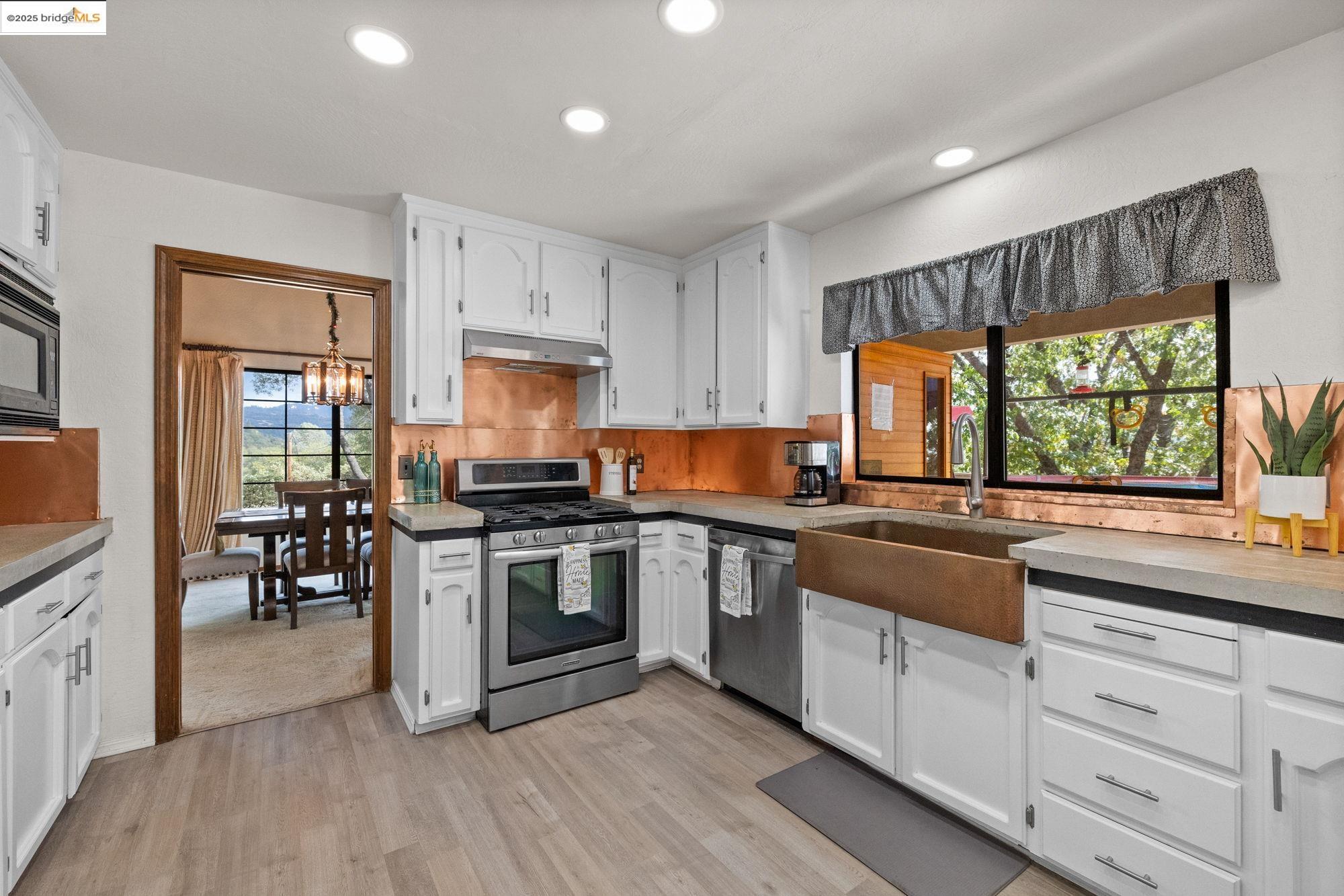 21950 Paseo De Los Portales Road Sonora, CA 95370 - Photo 10 of 47 a kitchen with stainless steel appliances granite countertop hardwood floor sink stove dining table and chairs