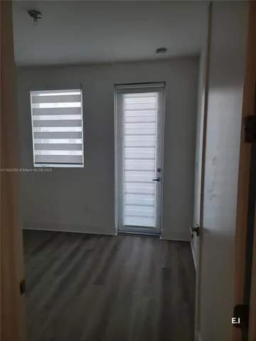 an empty room with wooden floor windows and closet