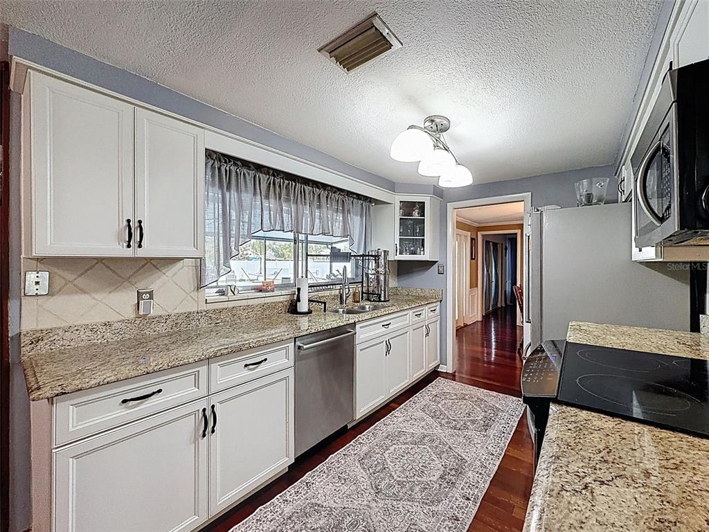 1602 Alder Way Brandon, FL 33510 - Photo 25 of 64 a kitchen with stainless steel appliances granite countertop a sink dishwasher stove and refrigerator with wooden floor