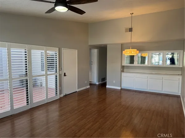 an empty room with wooden floor a ceiling fan and windows