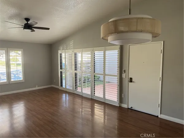 a view of an empty room with a window and wooden floor