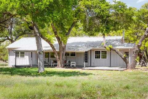 a front view of a house with a yard and large trees