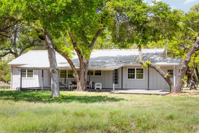 a front view of a house with a yard and large trees