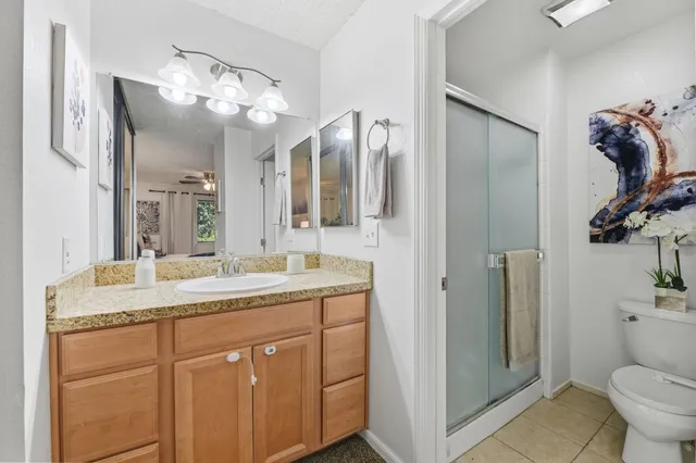 a bathroom with a granite countertop sink a toilet and a mirror