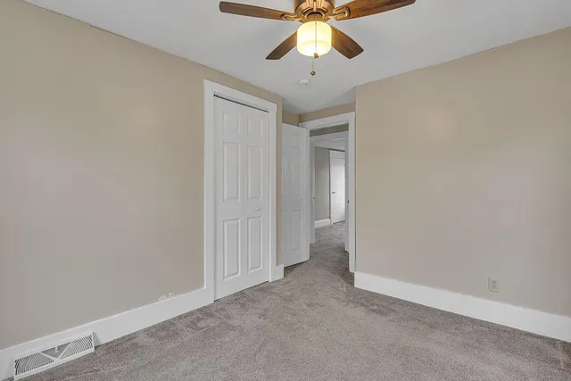 an empty room with a chandelier fan and closet