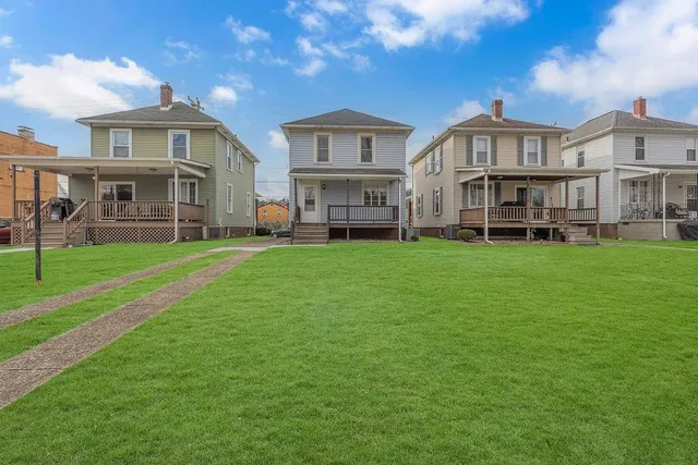 a view of house with a big yard and large trees