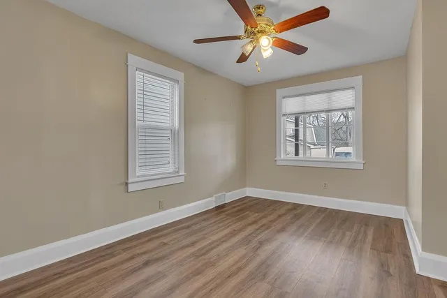 a view of an empty room with window and wooden floor
