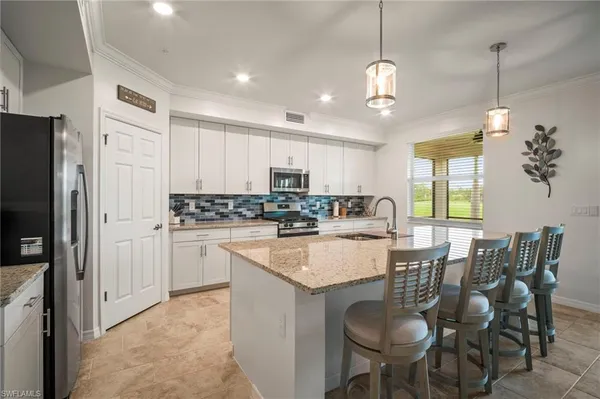 a kitchen with stainless steel appliances granite countertop a refrigerator a sink dishwasher a dining table and chairs with wooden floor