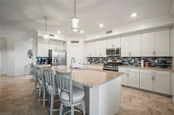 a kitchen with stainless steel appliances granite countertop a stove a sink a center island and chairs