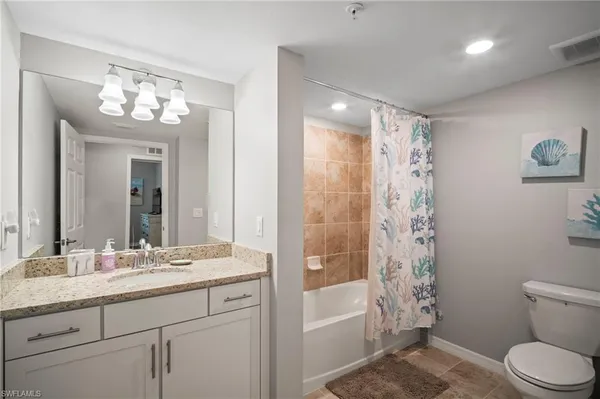 a bathroom with a sink a toilet a mirror a vanity and bathtub