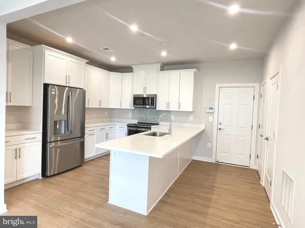 a large kitchen with a center island wooden floor stainless steel appliances and windows