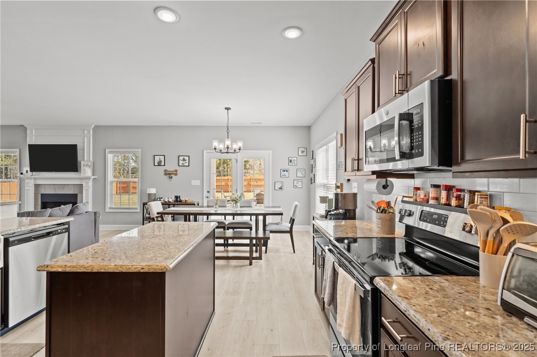 6438 Calloway Road Aberdeen, NC 28315 - Photo 14 of 50 a kitchen with stainless steel appliances granite countertop a stove top oven a sink dishwasher a dining table and chairs with wooden floor
