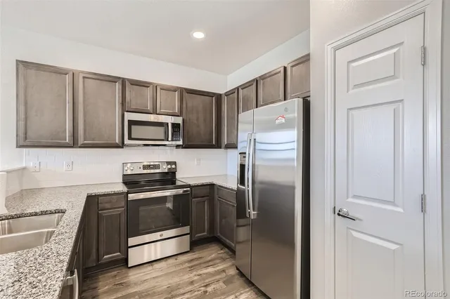 a kitchen with stainless steel appliances granite countertop a refrigerator a stove top oven a sink and dishwasher