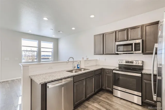 a kitchen with stainless steel appliances a stove sink microwave and window
