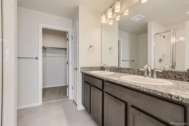 a bathroom with a granite countertop double vanity sink and a mirror
