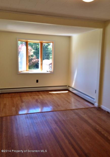374 Maple Lake Road Moscow, PA 18444 - Photo 13 of 36 an empty room with wooden floor and windows with curtains