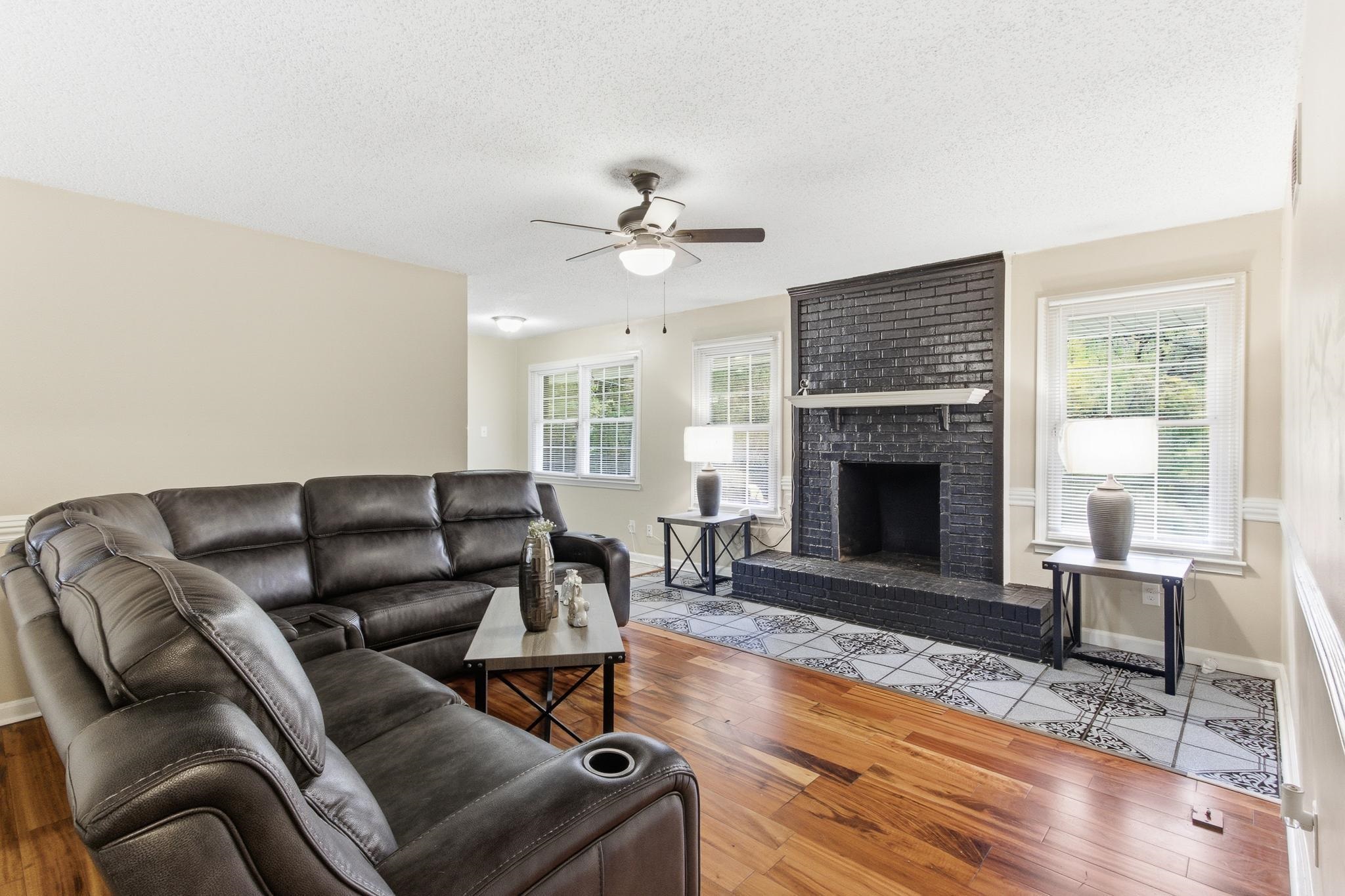 5002 Benjestown Road Memphis, TN 38127 - Photo 6 of 29 Living area featuring plenty of natural light, a textured ceiling, wood-type flooring, a brick fireplace, and ceiling fan