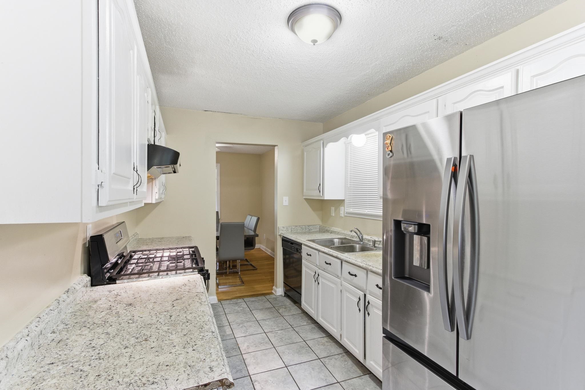 5002 Benjestown Road Memphis, TN 38127 - Photo 9 of 29 Kitchen with stainless steel fridge with ice dispenser, white cabinets, range with gas stovetop, a textured ceiling, and light tile patterned floors