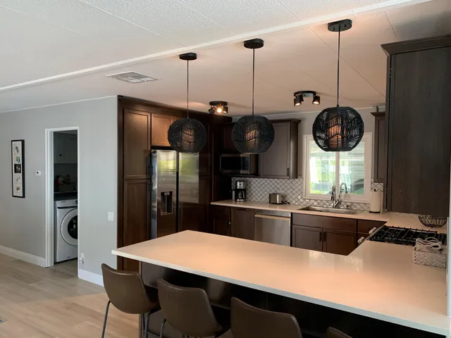 a kitchen with stainless steel appliances a table a sink and refrigerator