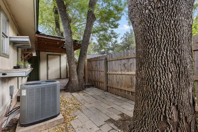 a backyard of a house with wooden fence and large trees