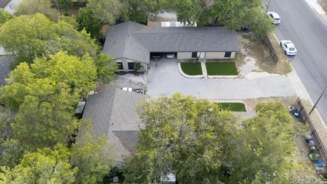 an aerial view of a house with yard and trees all around