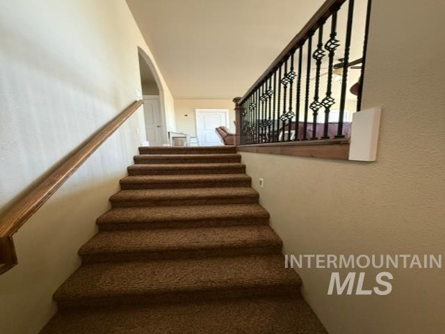 1520 Scheloske Road Weiser, ID 83672 - Photo 25 of 42 Carpeted staircase featuring a wood handrail and wrought iron balusters