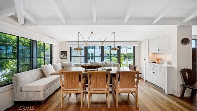 a dining room with wooden floor glass walls and glass windows