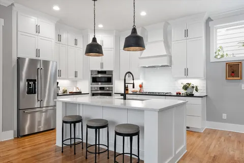 a kitchen with stainless steel appliances granite countertop a sink a stove a refrigerator and island with wooden floor