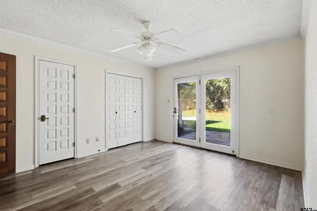 a view of an empty room with a window and wooden floor