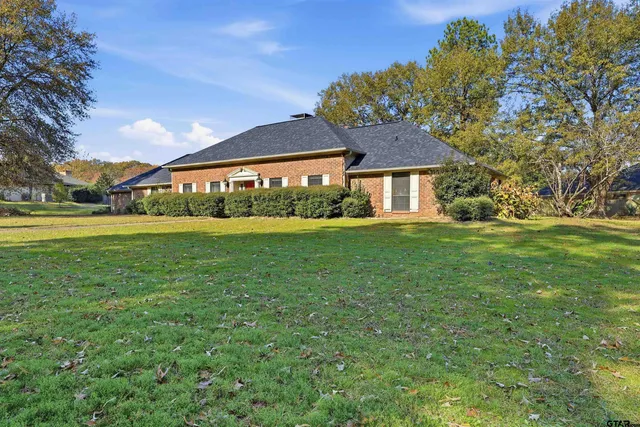 a view of a house with a yard and a large tree
