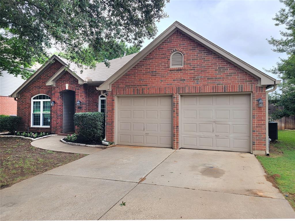 1604 Knoll Ridge Circle Corinth, TX 76210 - Photo 4 of 37 Traditional brick exterior featuring a two-car garage, arched entry, and established landscaping