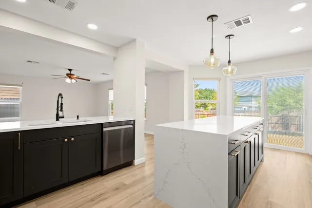 a kitchen with stainless steel appliances granite countertop a sink a stove and a wooden floors