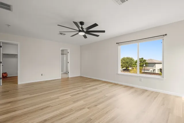 a view of empty room with wooden floor and fan