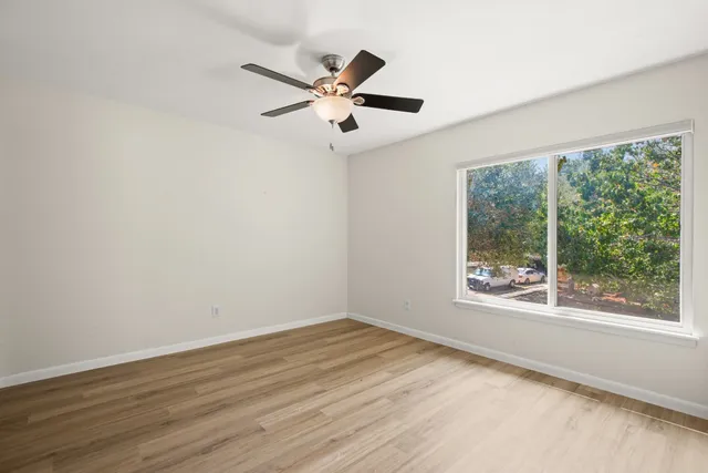 a view of empty room with wooden floor and fan