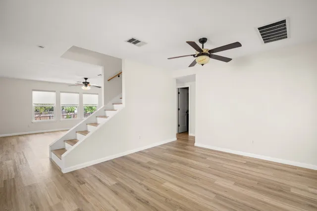 a view of a living room with wooden floor and a ceiling fan