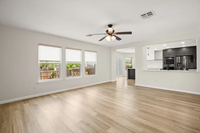 a view of an empty room with window and wooden floor