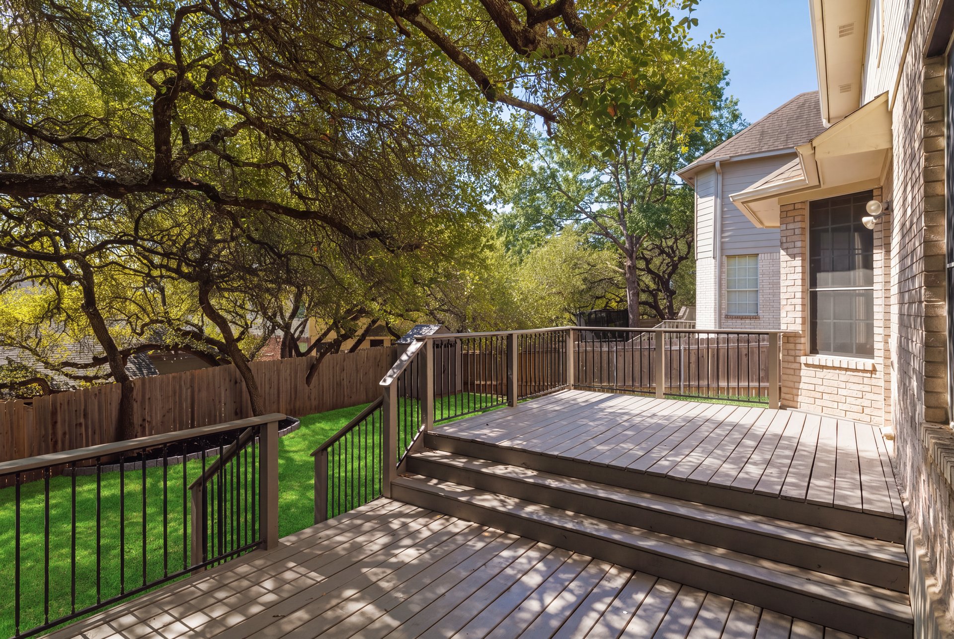 7113 Bending Oak Road Austin, TX 78749 - Photo 33 of 39 Mature trees shade a multilevel wooden deck overlooking the fenced grassy backyard.