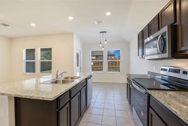 a kitchen with granite countertop kitchen island stainless steel appliances a sink stove and cabinets
