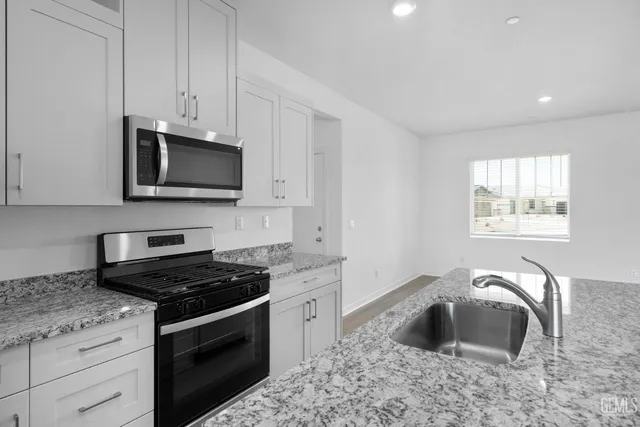 a kitchen with granite countertop a stove and a microwave