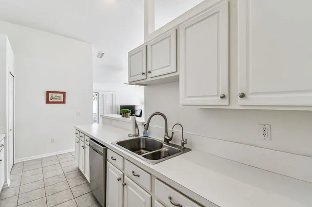 a kitchen with white cabinets a sink and a stove with wooden floor