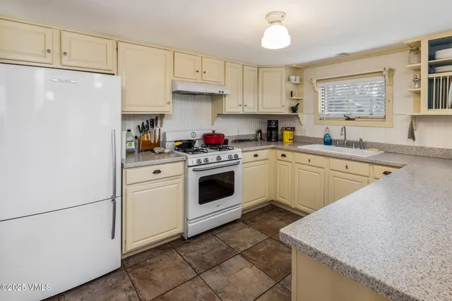 a kitchen with a sink a stove a refrigerator and cabinets